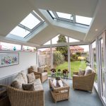 A conservatory with a glass roof and wicker furniture providing Performance Conservatories in Tetbury.